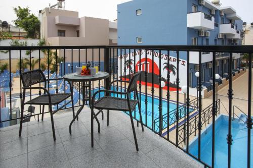 a balcony with a table and chairs next to a swimming pool at Happy Days in Malia