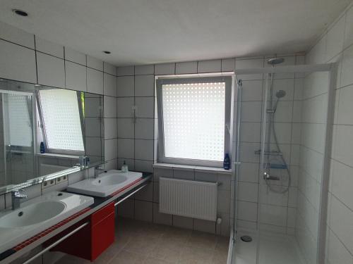La salle de bains est pourvue de 2 lavabos, d'une douche et d'une fenêtre. dans l'établissement Privatzimmer an der Uniklinik Mainz, à Mayence