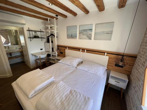 a bedroom with a white bed and a desk at On the Square Suites in Split