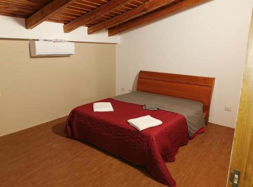 um quarto com uma cama vermelha com duas toalhas em Etnadia em Santa Maria di Licodia