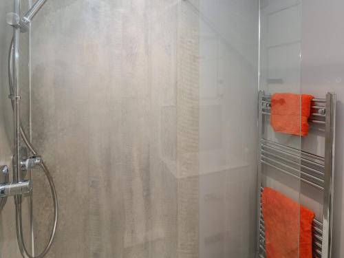 y baño con ducha y toallas de color naranja. en Primrose Cottage en Tenby