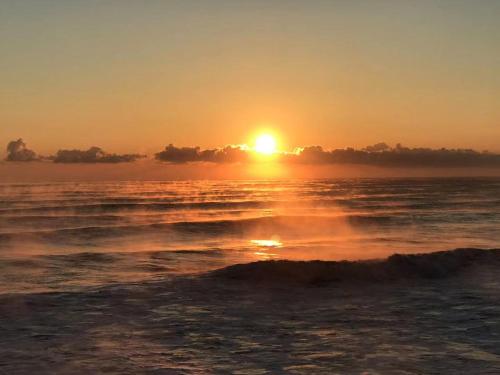 a sunset on the beach with the sun in the horizon at 旭日山荘 in Ōdera