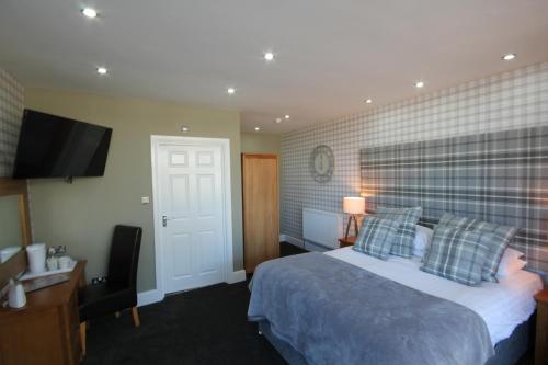a hotel room with a bed and a flat screen tv at The Sunningdale in Bamburgh