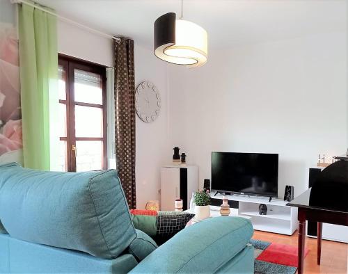 a living room with a blue couch and a television at Coquetty Housing In Santander Bay in El Astillero