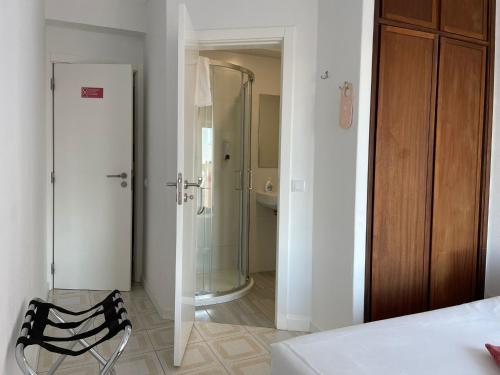 a bathroom with a shower and a chair in a room at Stella di Mare Alojamento Local in Figueira da Foz
