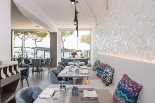 una sala da pranzo con tavoli, sedie e finestre di Hotel Planamar by Escampa Hotels a Platja  d'Aro