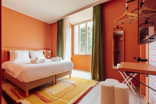 a bedroom with orange walls and a bed and a television at La Loge Gogaille - Fernand Rabier - accès autonome in Orléans