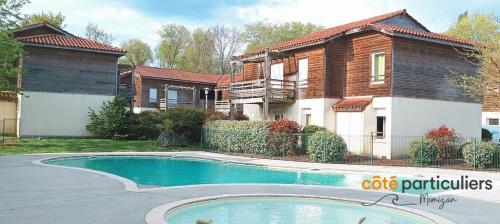 une maison avec une piscine devant une maison dans l'établissement LES TERRASSES DU LAC 26 - Apt T3 au bord du Lac, à Aureilhan