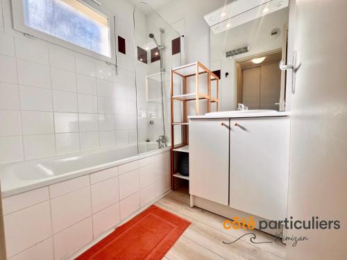 une salle de bain blanche avec une baignoire et un lavabo dans l'établissement LES TERRASSES DU LAC 26 - Apt T3 au bord du Lac, à Aureilhan
