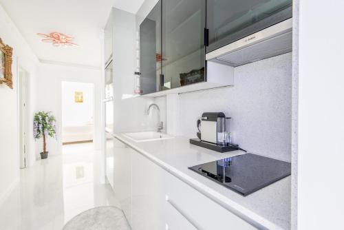 a white kitchen with a sink and a microwave at La Perle Bleue - Central - Vue Mer - Wifi in Roquebrune-Cap-Martin
