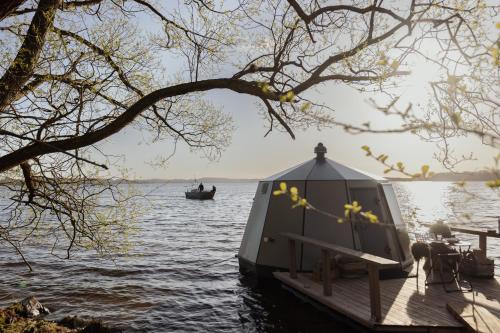 ein kleines Boot auf dem Wasser neben einem Dock in der Unterkunft Yggdrasil Igloo Skåne in Höör