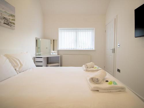 a bedroom with a white bed with towels on it at Pass the Keys Modern Coastal Cottage in North Shields
