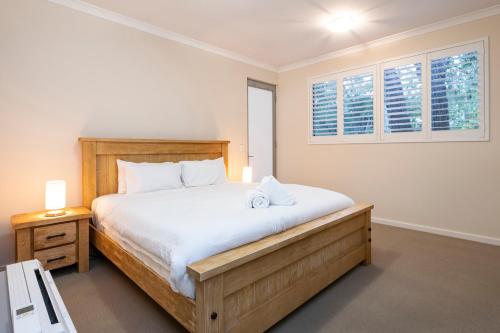a bedroom with a large bed and two windows at Whatmans Beach House - on the water's edge in Dunsborough