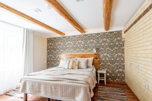 a bedroom with a bed and a wall covered in wallpaper at Alice Backyard-Holiday home and Spa in Pärnu