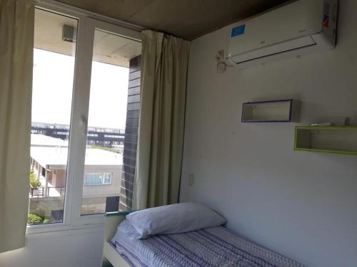 um quarto com uma cama e uma grande janela em Linda Bay Beach & Resort em Mar de las Pampas