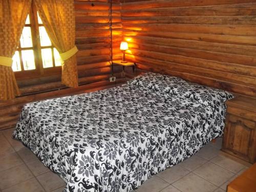 a black and white bed in a room with wooden walls at Cabañas Troncos Del Salto in Potrerillos