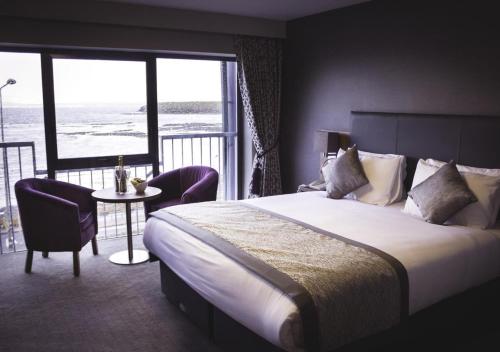 a bedroom with a bed and a table and a balcony at Allingham Arms Hotel in Bundoran