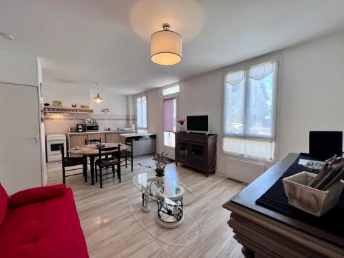 een woonkamer met een rode bank en een keuken bij Maison des Papillons - Jolie Maison - Proche Centre Brive in Brive-la-Gaillarde