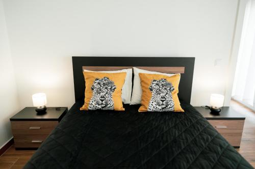a bedroom with a black bed with orange pillows at Gold Apartment Ferrel I in Ferrel