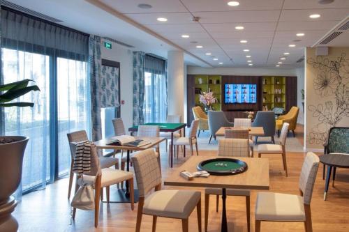 - une salle d'attente avec des tables, des chaises et des fenêtres dans l'établissement Résidence Services Seniors DOMITYS - LA BELLE EPOQUE, à Dinard