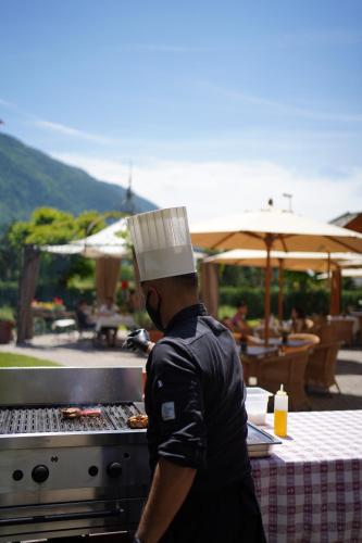a man in a chefs hat cooking on a grill at Hotel Du Lac in Molveno