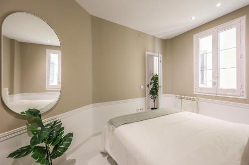 sypialnia z białym łóżkiem i lustrem w obiekcie Apartamento Embajadores XV w Madrycie