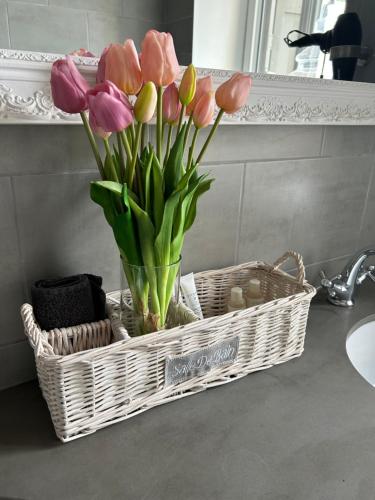 a basket with pink and yellow tulips in a bathroom at Provence Luberon Bonnieux location gite chez Marcelle in Bonnieux