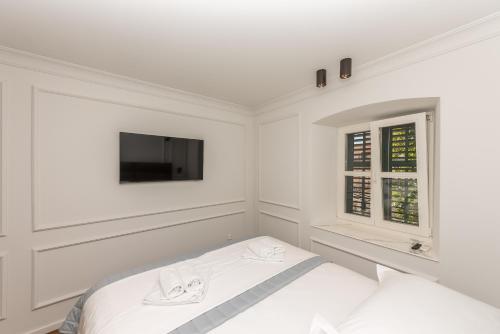 a white bedroom with a bed and a flat screen tv at Palace Heritage Apartments in Makarska