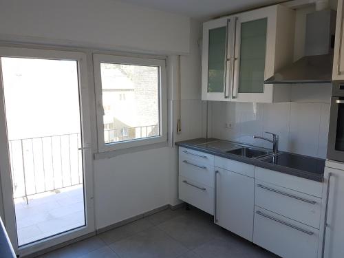 uma cozinha com armários brancos, um lavatório e uma janela em Joanna Apartment- MA City 1 em Mannheim