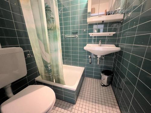 ein grün gefliestes Bad mit einem WC und einem Waschbecken in der Unterkunft Ferienpark Sierksdorf App 53 - Strandlage in Sierksdorf