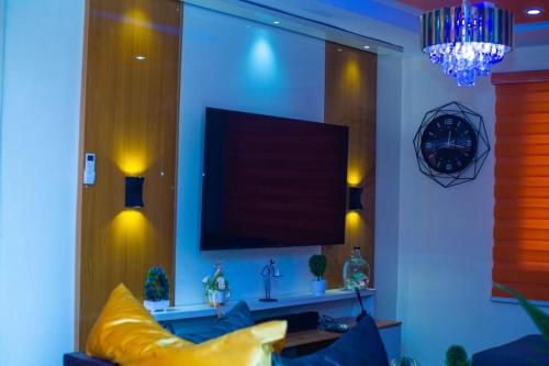 sala de estar con TV de pantalla plana en la pared en House 11 en Ibadán