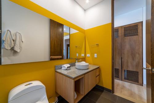 Baño amarillo con aseo y lavamanos en Cozy Loft in Parque 93, en Bogotá