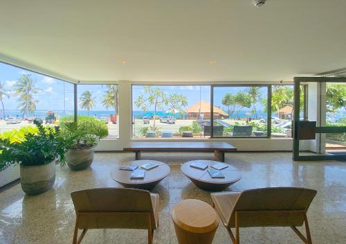 - un salon avec deux chaises, une table et des fenêtres dans l'établissement Hotel Ponta Verde Maceió, à Maceió