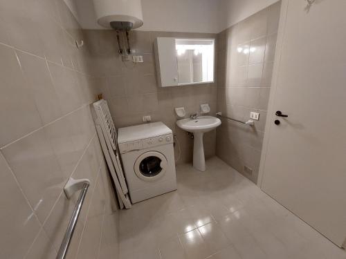 baño pequeño con lavadora y lavamanos en Golden Riviera No 7 en Lignano Sabbiadoro