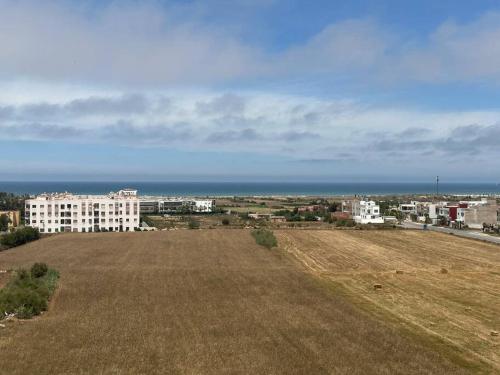 an empty field with a view of the ocean and buildings at Appartement vue sur mer sidi Rahal in Sidi Rahal