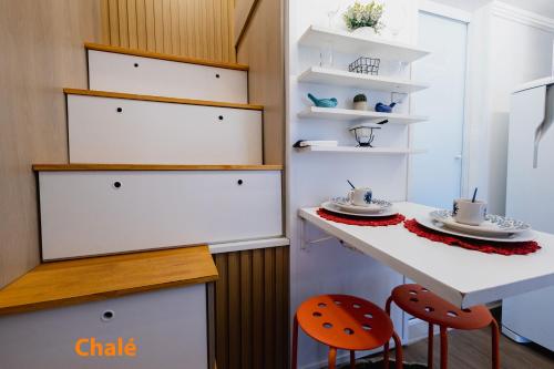 a kitchen with white cabinets and a counter with orange chairs at Minicasa Brasileira in Sorocaba