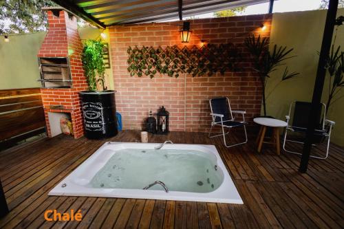 a hot tub on a deck with a brick wall at Minicasa Brasileira in Sorocaba