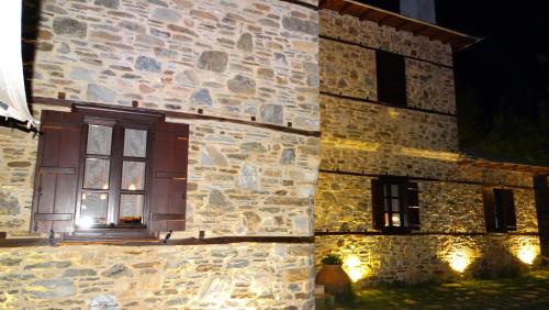 a stone building with a window at night at Iliopetra Suites in Agios Lavredios