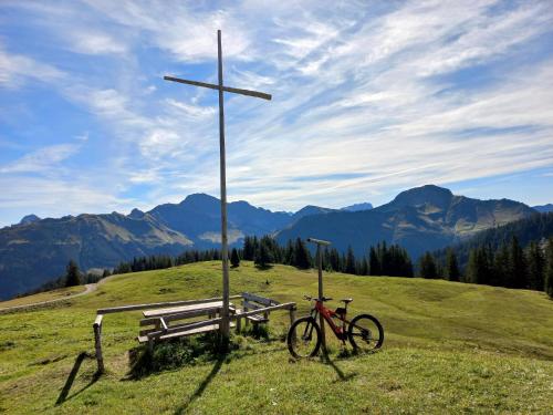 a bike parked next to a bench and a cross at Ländle Hotel in Damuls