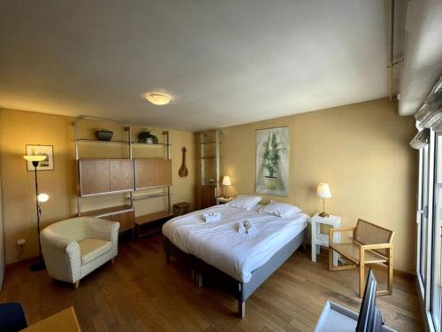 a bedroom with a large white bed and a chair at Tania, Hyper centre-ville de Caen avec parking in Caen