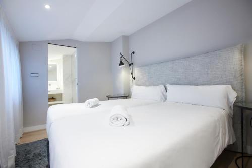 uma cama branca com duas toalhas em cima em U-Sense Madrid Santa Ana em Madri