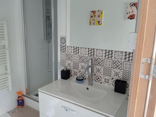 La salle de bains blanche est pourvue d'un lavabo et d'une douche. dans l'établissement ChicEthnik! Maison de ville, 3 chambres, 6 places., à Besançon