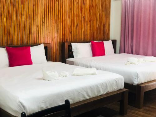 2 Betten in einem Zimmer mit roten und weißen Kissen in der Unterkunft กอบสุข รีสอร์ท2 k04 in Ban Ton Liang