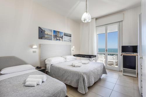 a bedroom with two beds and a view of the ocean at Hotel Caesar in Lido di Savio
