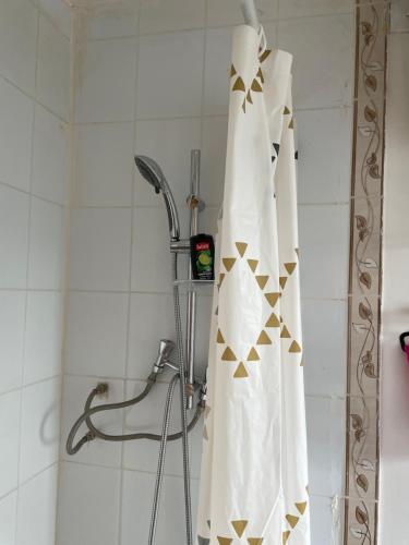 une douche avec rideau de douche blanc et triangles d'or dans l'établissement Douchedodo, à Paris