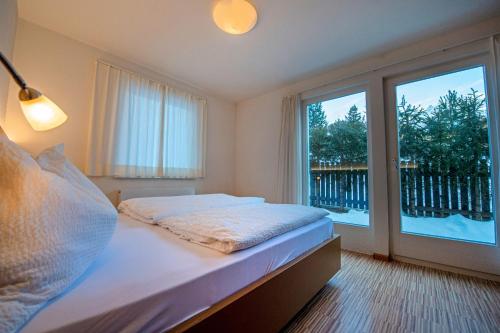 a bedroom with a bed and a large window at The Muse Apartments in Selva di Val Gardena