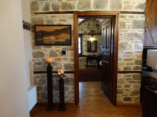 a hallway with a stone wall and an open door at Iliopetra Suites in Agios Lavredios