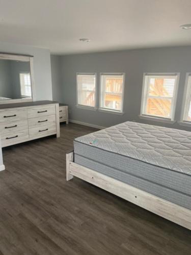 a bedroom with a bed and a dresser and windows at 20 Dupont Beach House in Seaside Heights