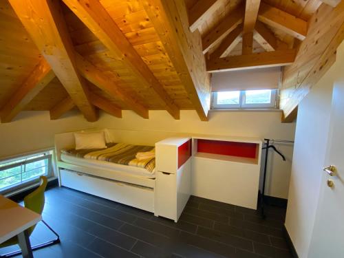 Un pequeño dormitorio con una cama en una habitación con techos de madera. en Small apartments in Collina d’Oro, en Agra