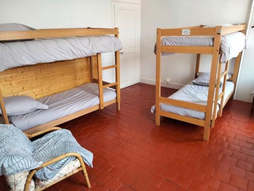 una stanza con due letti a castello e un pavimento in mattoni rossi di Gîte de groupe 2 à 12 personnes a Guillon